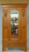 A late 19th century satin walnut wardrobe with central shaped bevelled mirror door flanked by Art