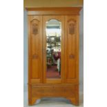 A late 19th century satin walnut wardrobe with central shaped bevelled mirror door flanked by Art