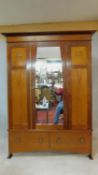 A late 19th century mahogany Arts and Crafts wardrobe with carved bud motif fitted with central