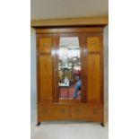 A late 19th century mahogany Arts and Crafts wardrobe with carved bud motif fitted with central