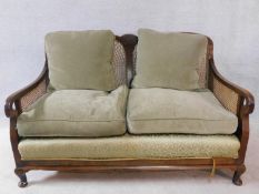 A mid century mahogany framed two seater bergere sofa with caned back and sides and squab cushions