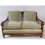 A mid century mahogany framed two seater bergere sofa with caned back and sides and squab cushions