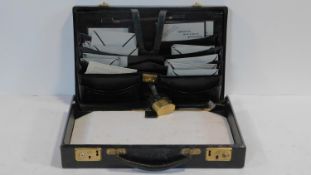 A vintage black leather documents attache case with brass fittings, fitted pocketed interior and
