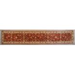 A Ziegler runner with allover scrolling floral design on a deep red field. L.335x60cm