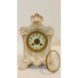 A porcelain hand painted antique gilded mantel clock with floral details and white enamel dial