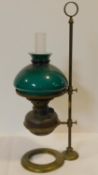A brass Victorian student/desk oil lamp with emerald green glass shade and mounted on a brass