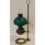 A brass Victorian student/desk oil lamp with emerald green glass shade and mounted on a brass