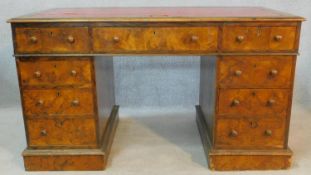 A mid 19th century burr walnut pedestal desk with inset tooled leather top above an arrangement of