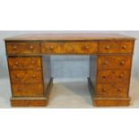 A mid 19th century burr walnut pedestal desk with inset tooled leather top above an arrangement of