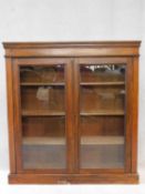 A 19th century walnut floor standing bookcase with glazed doors enclosing bookshelves on plinth