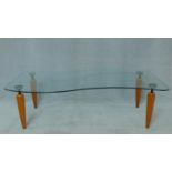 A contemporary low coffee table with shaped plate glass top on shaped beech supports. H.36 W.120 D.