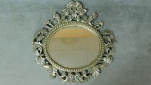 A circular wall mirror in scrolling floral silvered frame. 97x100cm