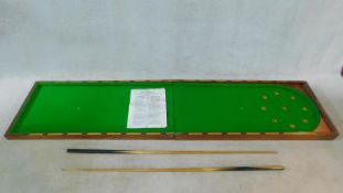 A vintage folding table top bagatelle table in mahogany case lined with green baize, with two cues