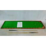 A vintage folding table top bagatelle table in mahogany case lined with green baize, with two cues