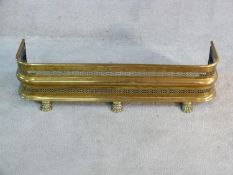 A 19th century pierced brass fender on lion's paw feet. 25x97cm