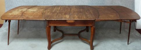 A vintage French oak extending dining table fitted with four extra leaves and integral end supports.