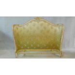 A mid century gilt and white painted bed head in floral damask resting on carved cabriole