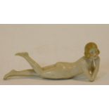 An antique hand painted porcelain figure of a nude lady lying with her leg up, mark to base and