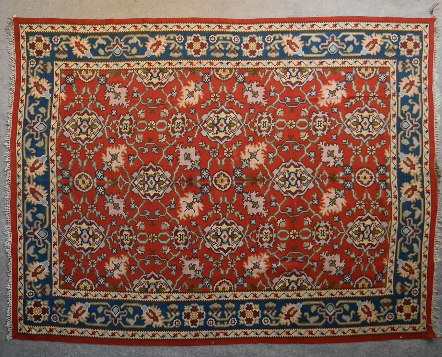 A Kilim with repeating scrolling floral design surrounded by an azure stylised flowerhead border.