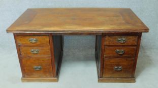 An Eastern teak pedestal desk with planked top and central kneehole section flanked by three