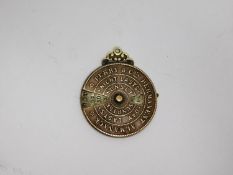 An antique Perry & Co permanent almanac brass dial watch fob, with cut out sections to show