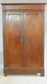 An antique French flame mahogany linen wardrobe with panel doors enclosing shelves on block feet.