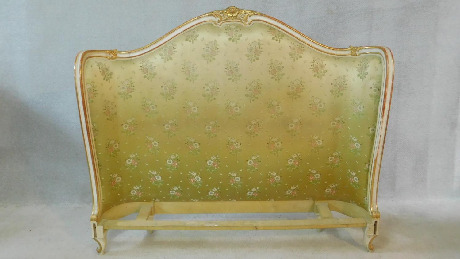 A mid century gilt and white painted bed head in floral damask resting on carved cabriole