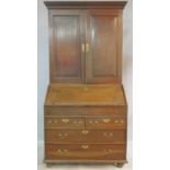 A Georgian country oak bureau bookcase with upper section fitted with fielded panel doors