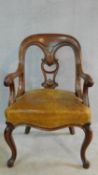 A mid Victorian mahogany desk chair with carved scrolling arms and stuffover leather upholstered and