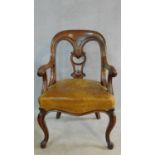 A mid Victorian mahogany desk chair with carved scrolling arms and stuffover leather upholstered and