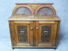 A 19th century oak side cabinet with shell carved superstructure above carved panel doors