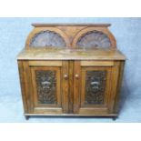 A 19th century oak side cabinet with shell carved superstructure above carved panel doors