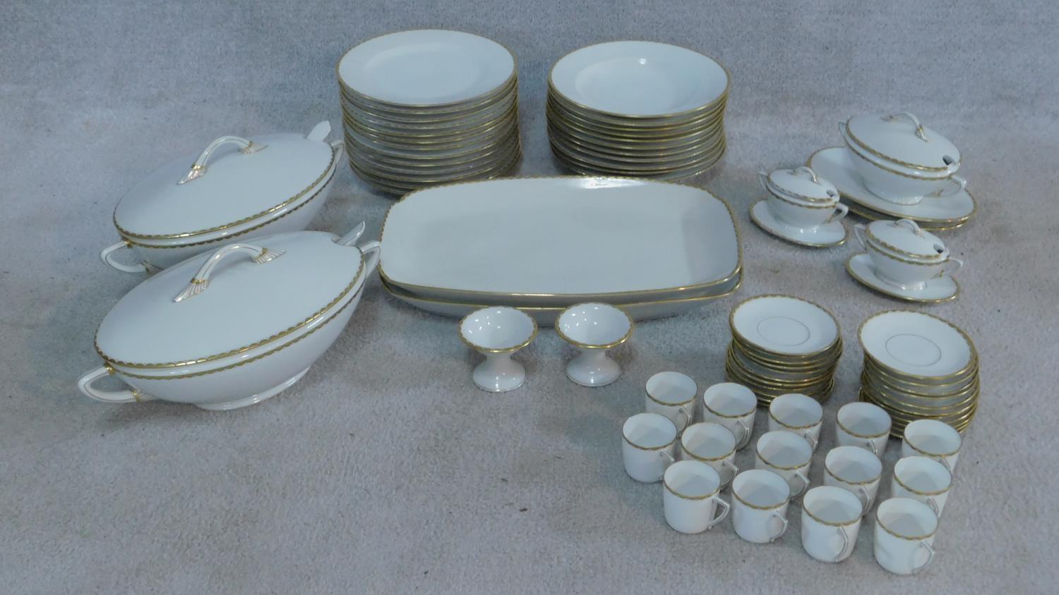 An extensive dinner service in white porcelain and gilt highlighted rims, marked Epiag,