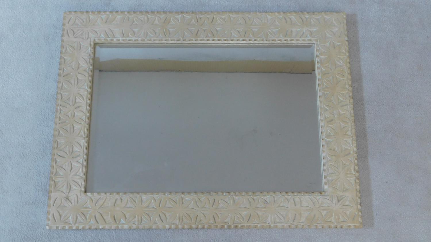 A vintage wall mirror in limed and carved frame fitted with bevelled plate. 122x92cm