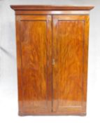 An early 19th century figured mahogany wardrobe with stepped moulded pediment above panel doors