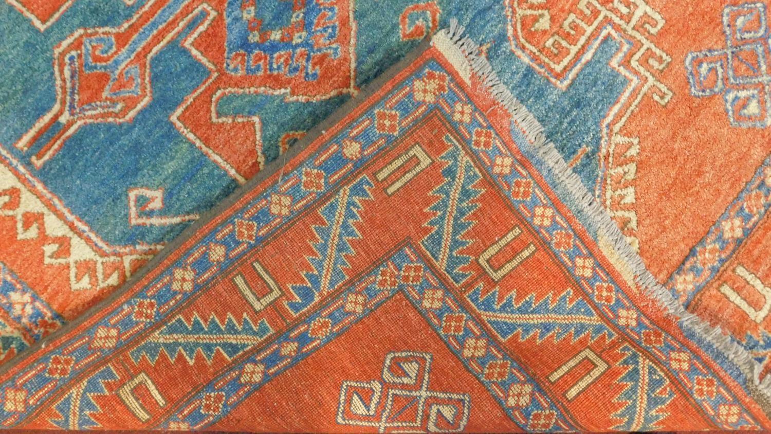 A Kazak rug with central medallion on azure ground within a pale burgundy field and stylised - Image 4 of 4