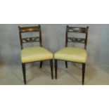 A pair of late Georgian mahogany dining chairs with carved backs above stuffover seats on turned