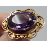 An antique pierced foliate design 9ct gold and amethyst oval brooch. Set to the centre with an