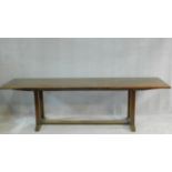 An oak refectory style dining table on chamfered stretchered square section supports on platform