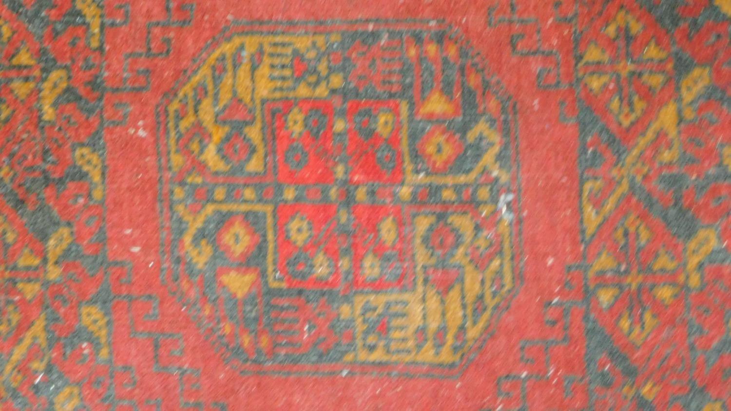 A Kazak rug with central lozenge medallions on a rouge field within floral multi borders and two - Image 3 of 4