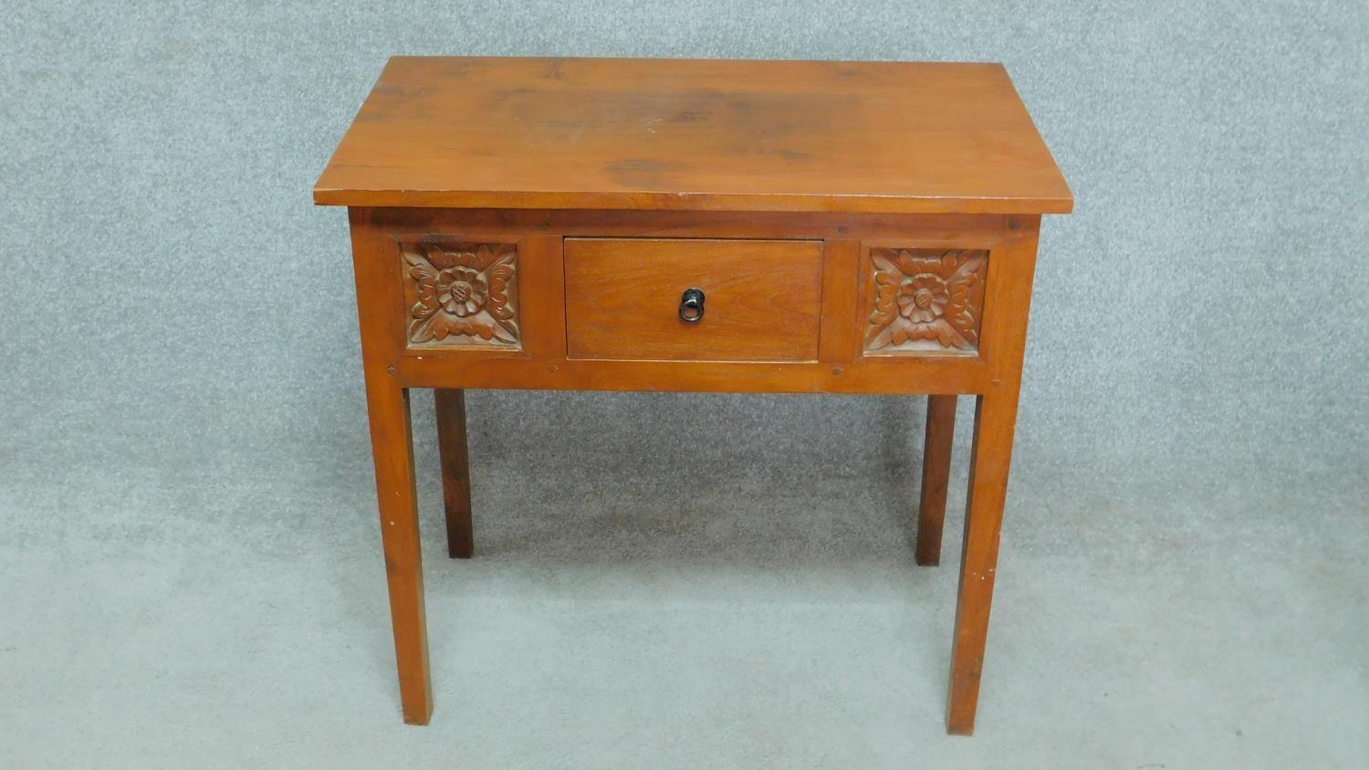 An Eastern teak side table fitted with frieze drawer flanked by floral carved panels on square