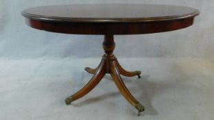 A 19th century mahogany tilt top dining table on quadruped swept supports on brass lion's paw