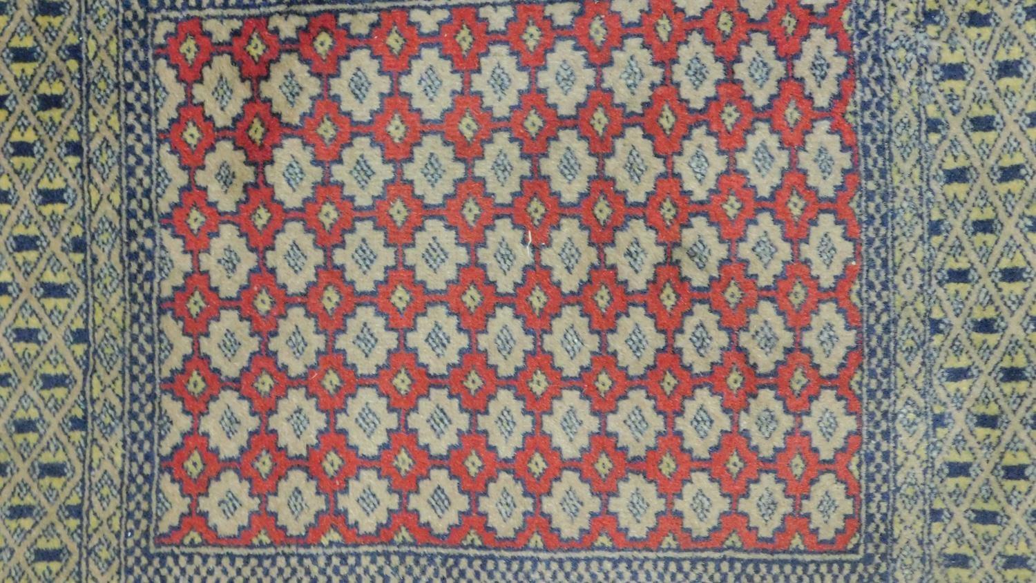 A Kazak rug with central lozenge medallions on a rouge field within floral multi borders and two - Image 4 of 4