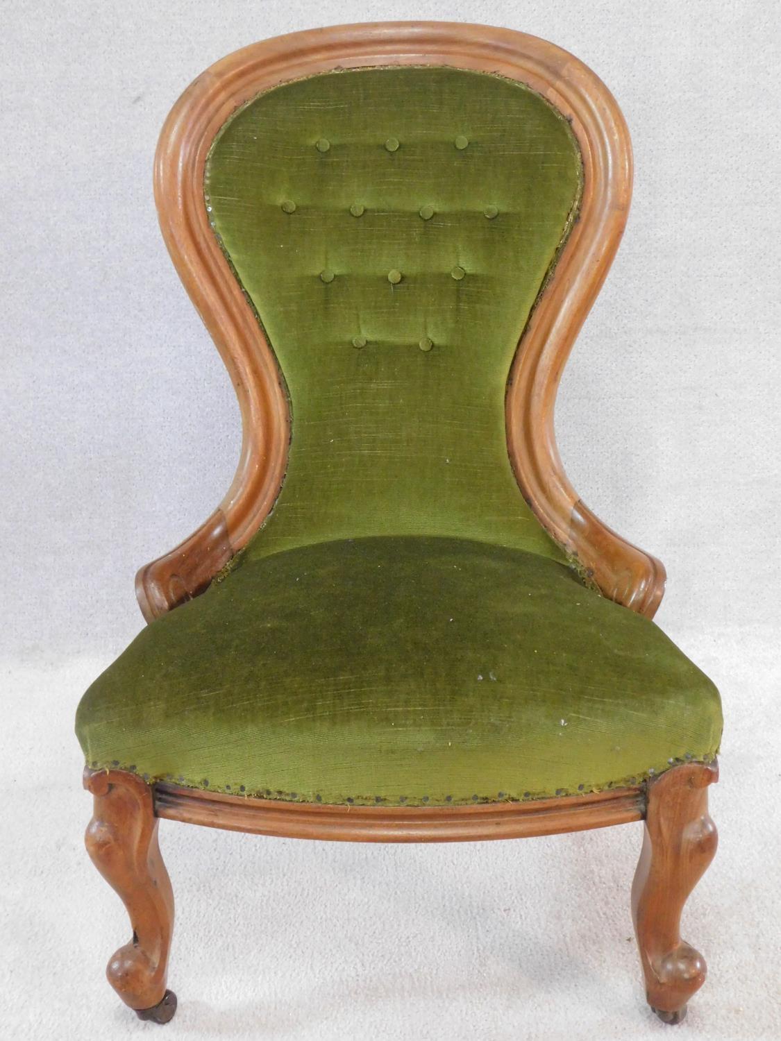 A Victorian mahogany framed spoon backed nursing chair in buttoned upholstery on carved cabriole