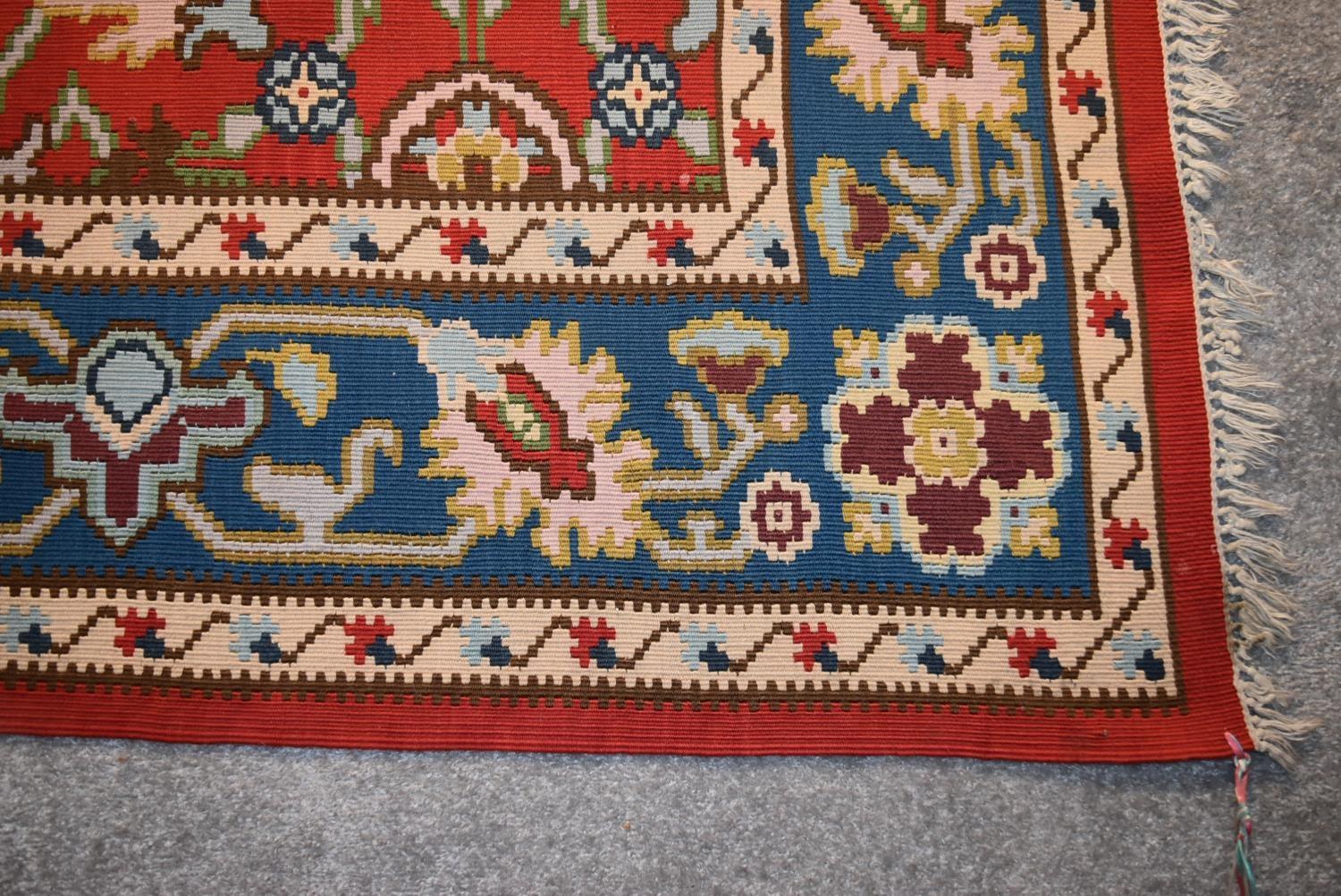 A Kilim with repeating scrolling floral design surrounded by an azure stylised flowerhead border. - Image 3 of 4