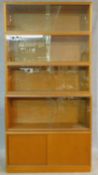 A mid century vintage teak bookcase with four upper sections with sliding glass doors above base