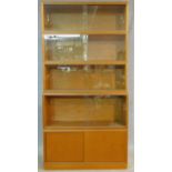 A mid century vintage teak bookcase with four upper sections with sliding glass doors above base