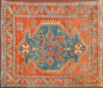 A Kazak rug with central medallion on azure ground within a pale burgundy field and stylised