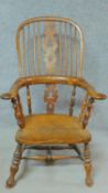 An antique country Windsor armchair with yew wood hooped back, spindles, pierced splat and arms with