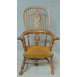 An antique country Windsor armchair with yew wood hooped back, spindles, pierced splat and arms with